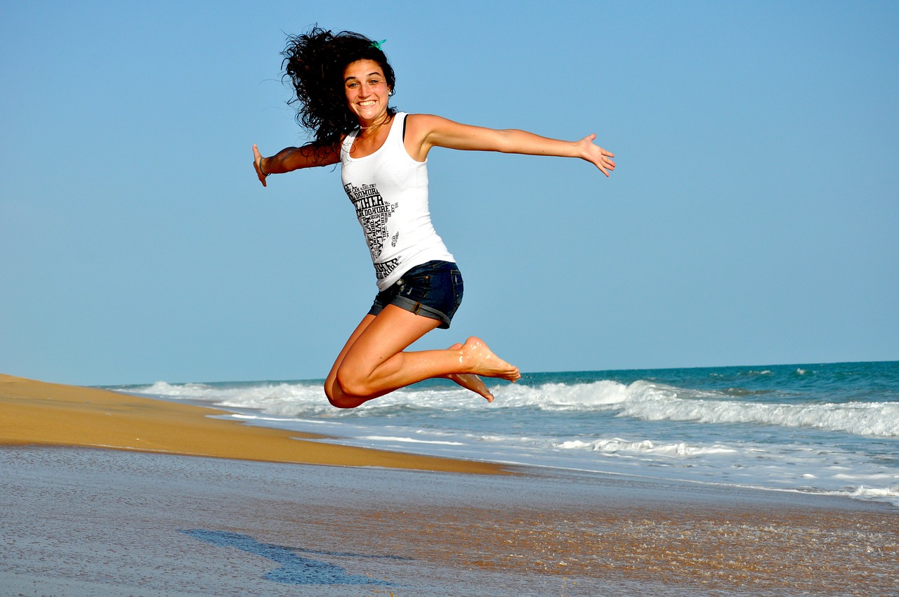 Woman jumping up in the air on the beach and smiling