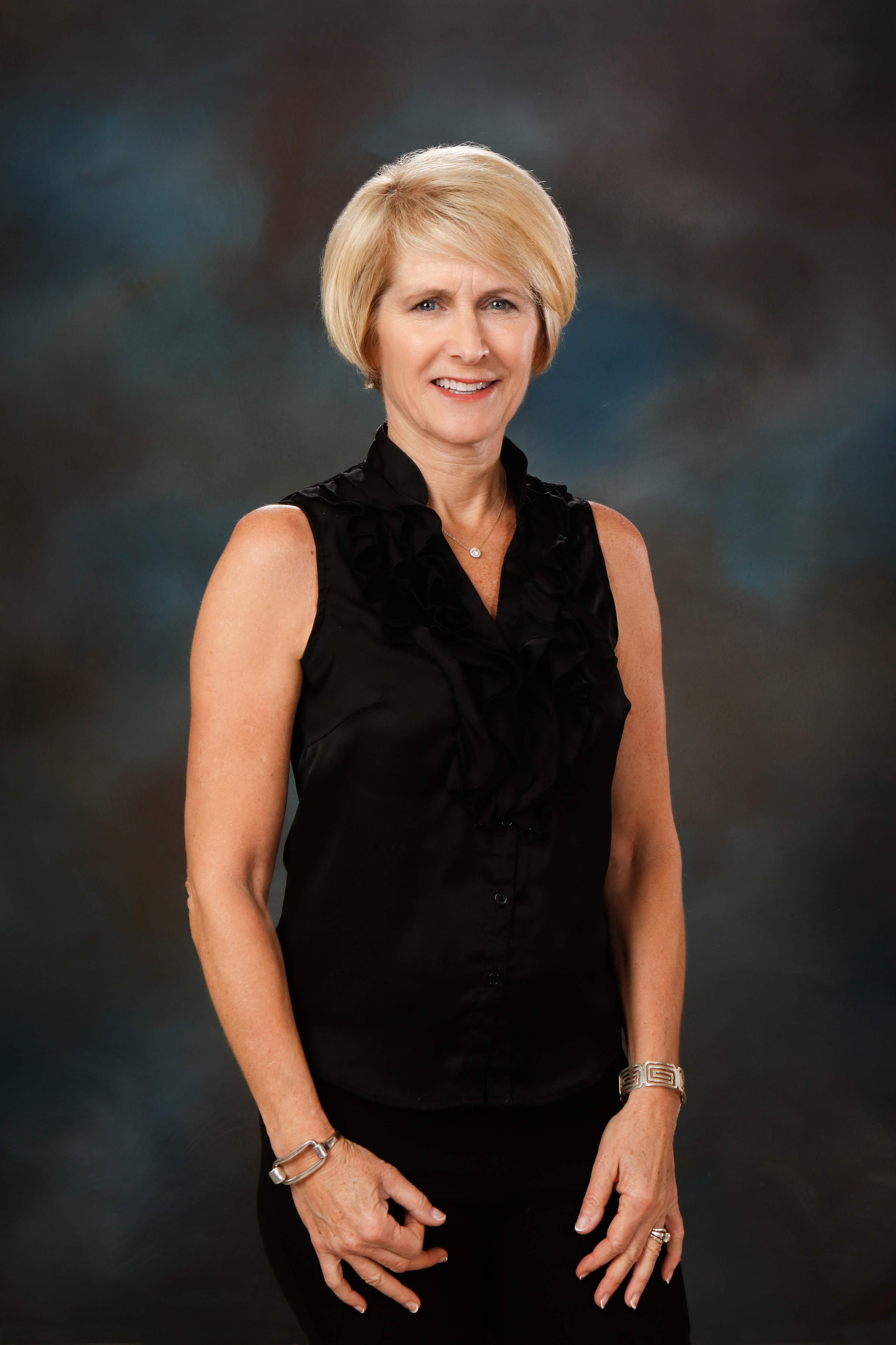 Dr. Lesli Bonar, DDS at Grand Dentistry in Escondido, CA, wearing a black dress in front of a blue background